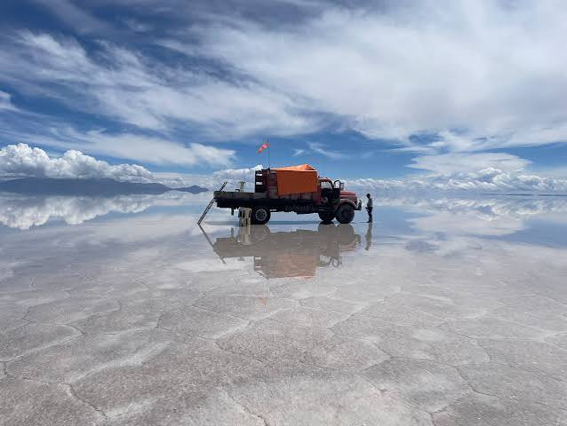 Tour vehicle on the Salar de Uyuni salt flats with sky reflection, Bolivia